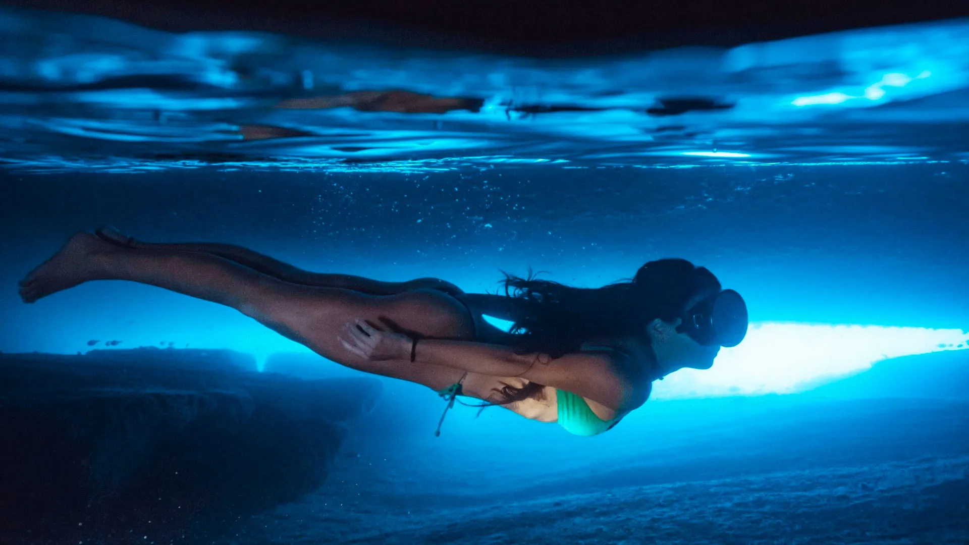 Freediving in the glowing blue water of the Gruta do Acaiá sea cave, Ilha Grande