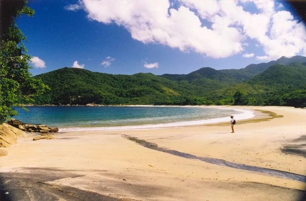 The wide, almost-empty horseshoe beach of Parnaioca with a lone figure, Ilha Grande